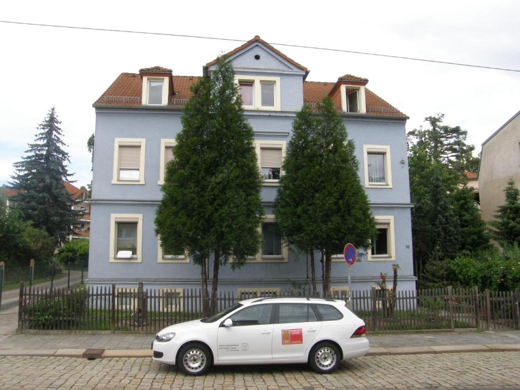 德累斯顿德累斯顿布利尼茨度假公寓酒店的停在蓝色房子前面的白色汽车