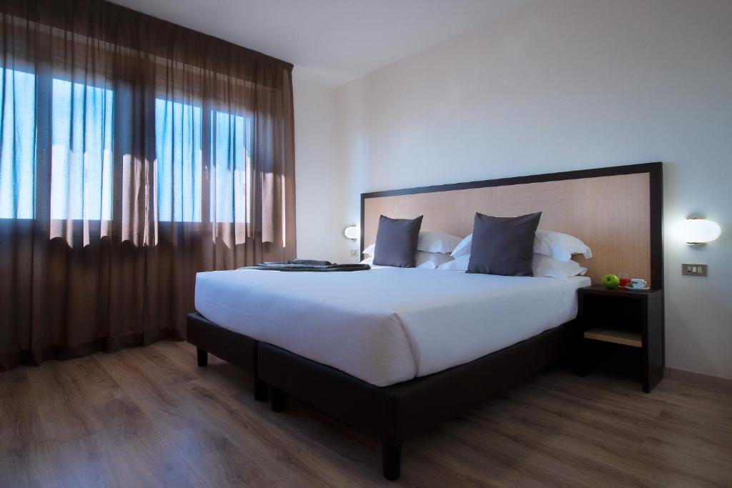 摩德纳CDH Hotel Modena的一间卧室设有一张大床和一个大窗户