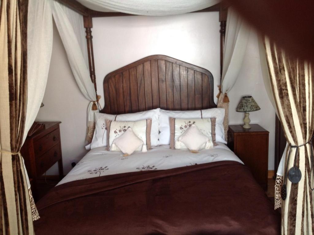 切尔滕纳姆爱丽丝旅馆的一间卧室配有一张大床和木制床头板
