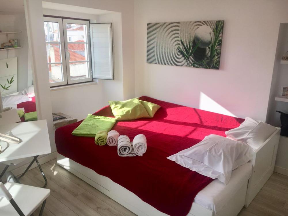 里斯本Pequeno Hostel Studio的一间卧室配有红色的床和2拖鞋