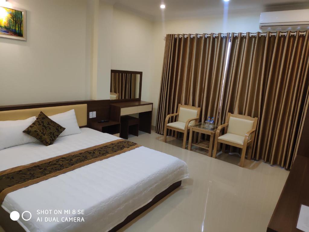 下龙湾Ngọc Anh Hotel的卧室配有一张床、一张桌子和椅子