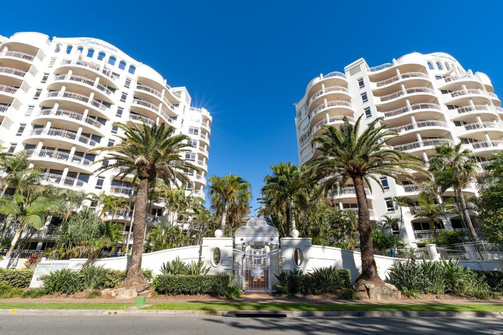 黄金海岸ULTIQA Burleigh Mediterranean Resort的两座高大的建筑,在街道前有棕榈树
