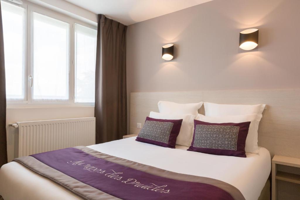 BrezollesThe Originals City, le Relais des Carnutes Brezolles Verneuil sur Avre的一间卧室配有一张带紫色枕头的大床