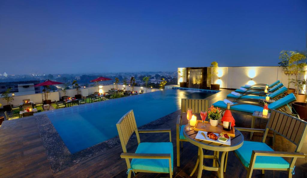 阿格拉Hotel Royale Regent的酒店屋顶设有游泳池、桌子和椅子