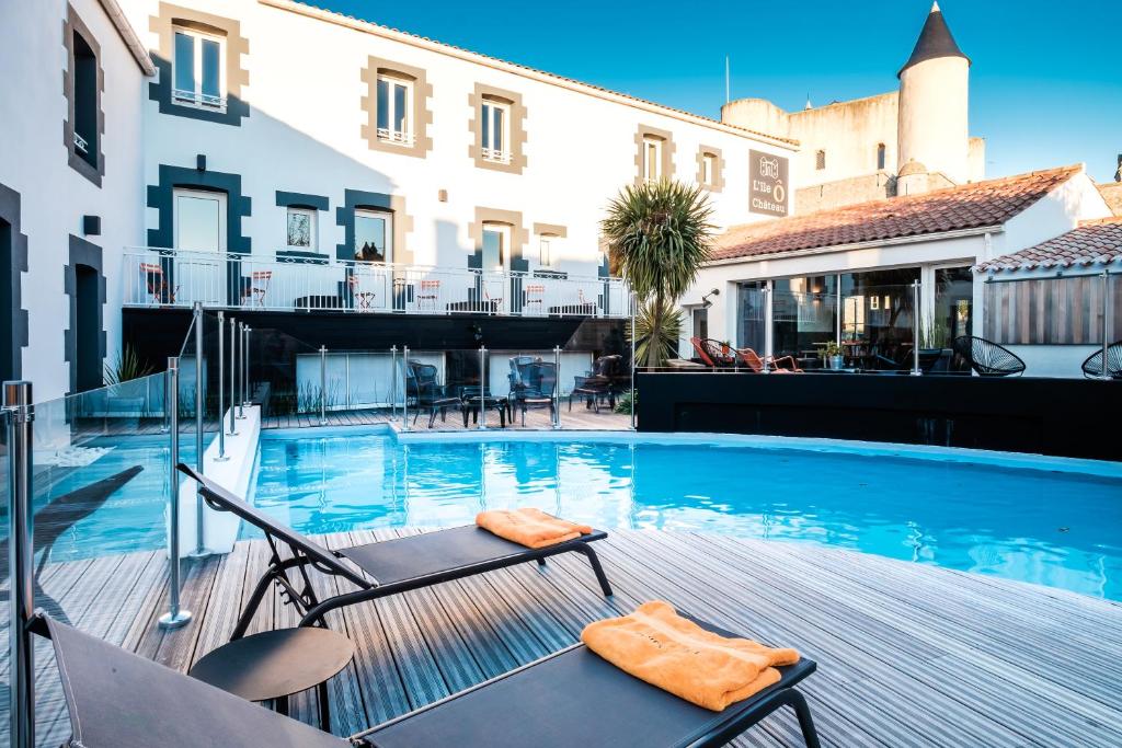 诺亚芒提亚岛屿城堡酒店的一座带椅子的游泳池,位于大楼旁