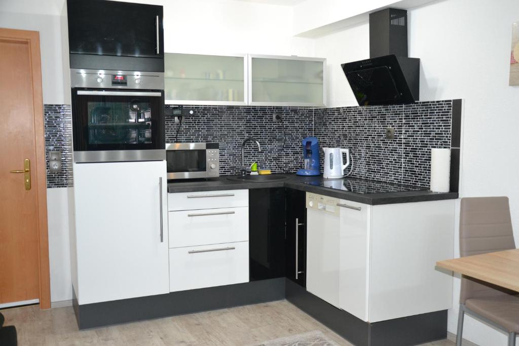 阿尔高内的伊门施塔特Ferienwohnung Emil的厨房配有白色橱柜和黑色台面