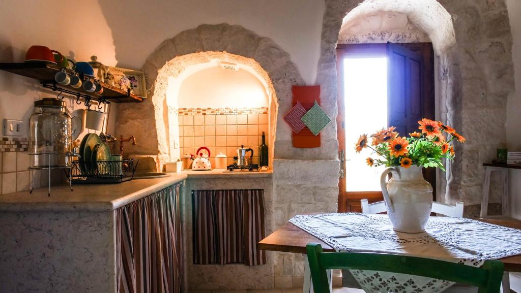 阿尔贝罗贝洛Trulli Barsento的厨房配有一张桌子,上面放着花瓶