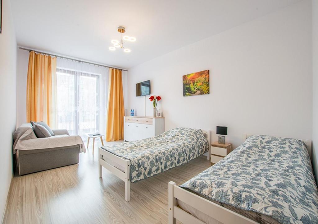 戈莱纽夫Central Apartments Goleniow的一间卧室设有两张床、一把椅子和一个窗户。