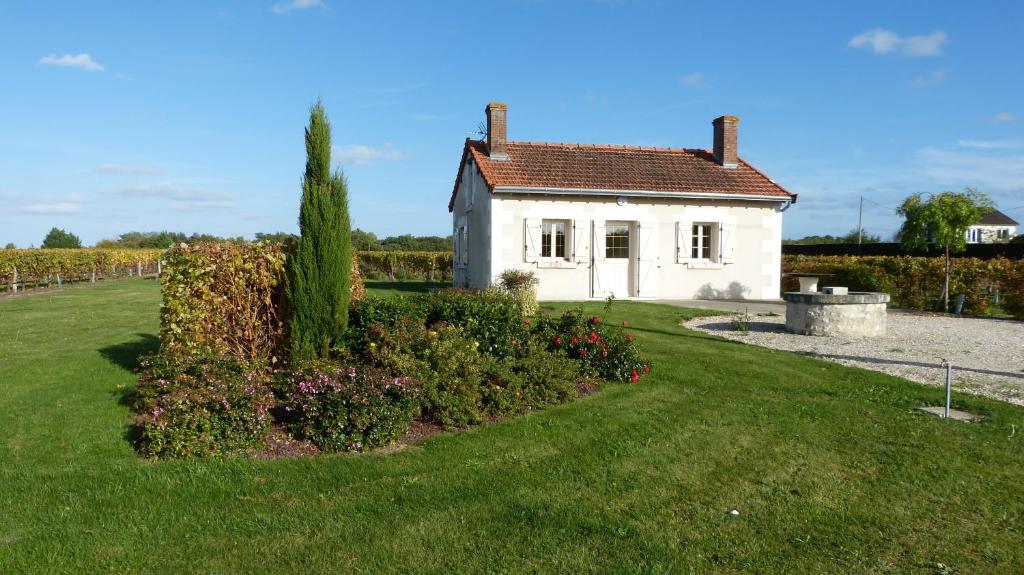 谢尔河畔圣乔治l'Ecrin au coeur des vignes的一座白色的小房子,前面设有一个花园