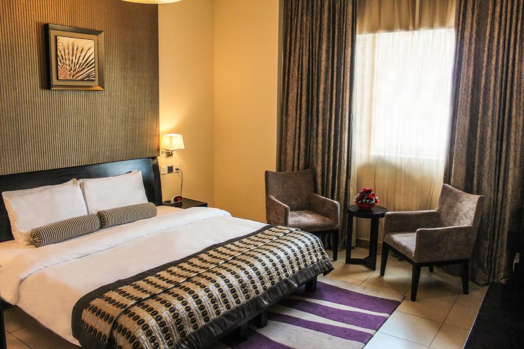 迪拜Dunes Hotel Apartment Oud Metha, Bur Dubai的酒店客房,配有一张床和两把椅子