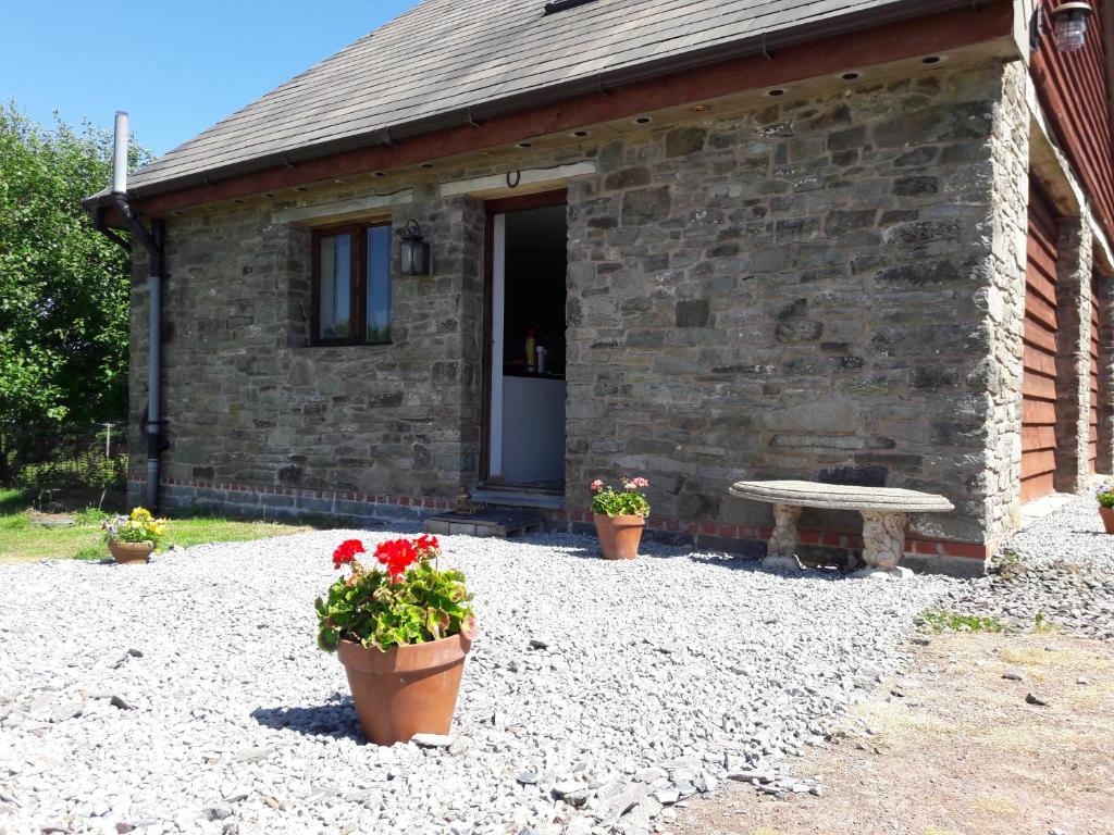 CrickadarnThe Barn Annexe, Cefn-Yr-Allt的石头房子,两盆花和长凳