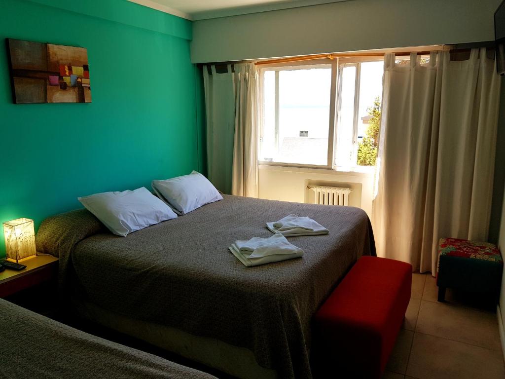 圣卡洛斯-德巴里洛切火烈鸟酒店的一间卧室设有一张带绿色墙壁和窗户的床。