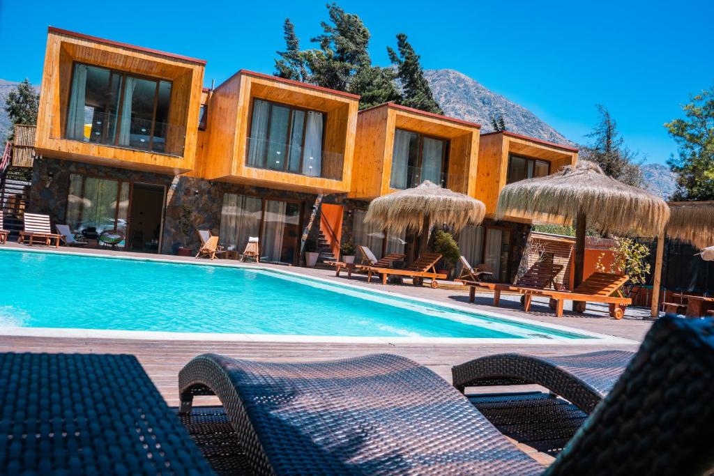 圣何塞德迈波Cajón del Maipo Lodge的一个带椅子和遮阳伞的游泳池的度假酒店