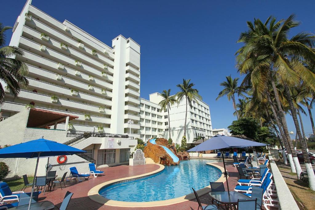 马萨特兰唐佩拉约太平洋海滩公寓的酒店设有带椅子和遮阳伞的游泳池