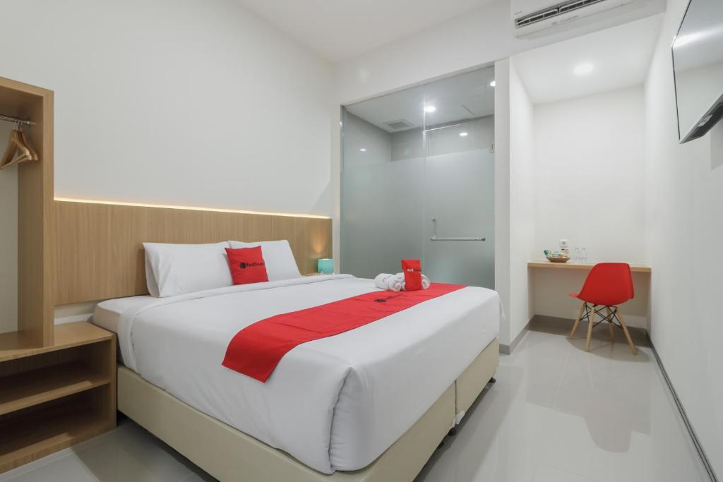 北干巴鲁RedDoorz near Mall SKA Pekanbaru的一间卧室配有一张大床和一张红色椅子