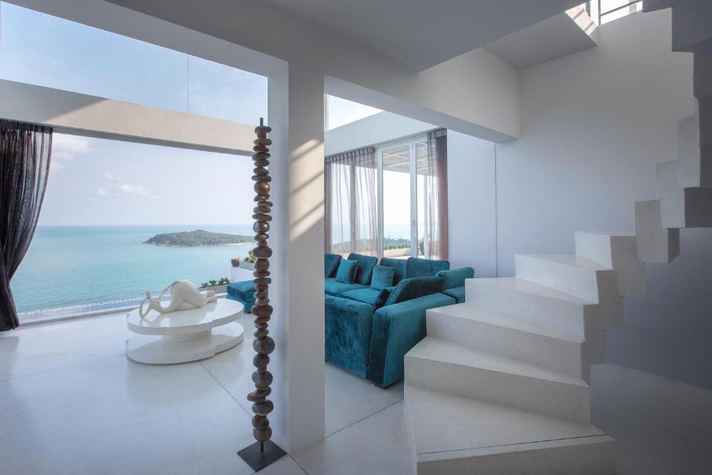 查汶特拉萨五卧日出海景别墅的客厅配有蓝色沙发,享有海景
