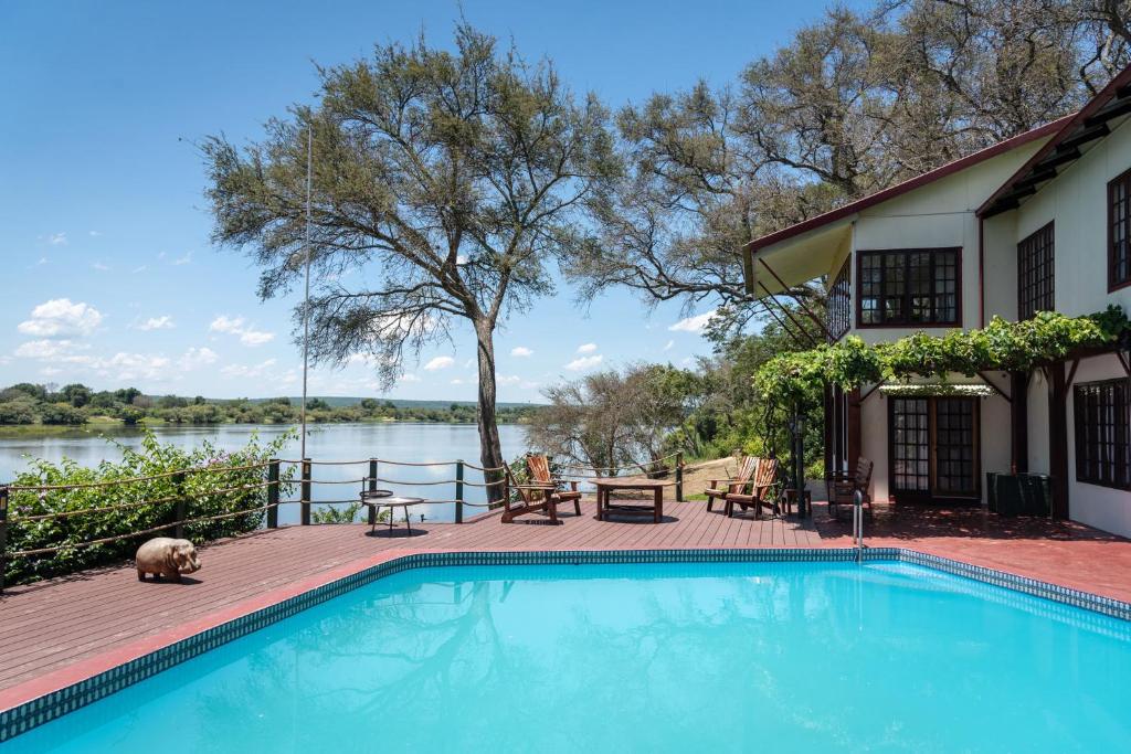 利文斯顿Kayube Zambezi River House的一座带湖泊的房子旁边的游泳池
