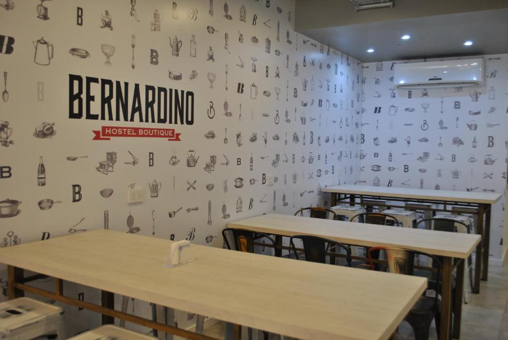 内乌肯Bernardino Hostel Boutique的一间设有桌子的用餐室和一面墙上的书写
