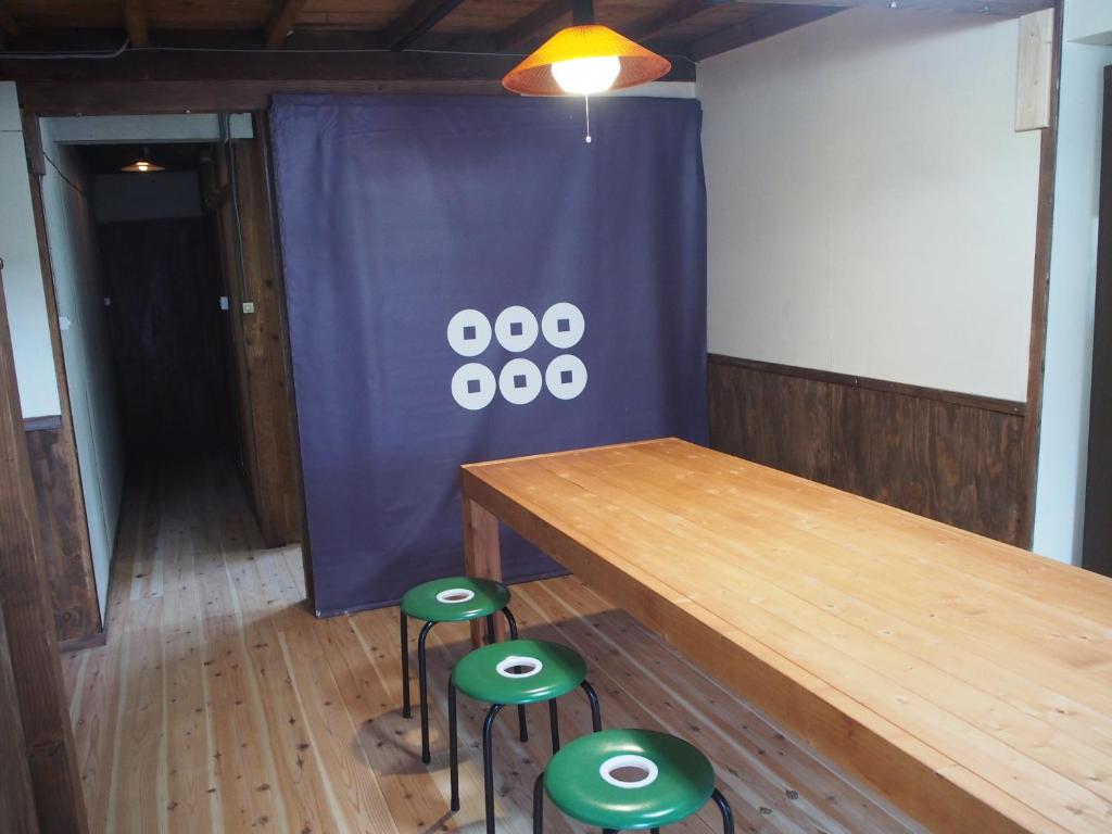 长野Guesthouse Matsushiro Walkers的一间会议室,配有一张木桌和绿色凳子