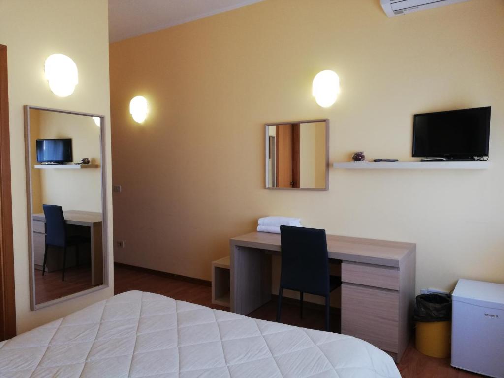 兰恰诺罗马酒店的一间卧室配有一张床、一张书桌和一台电视