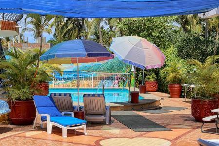 萨尤利塔Villas del Corazon - Iguana的游泳池畔的两把椅子和遮阳伞