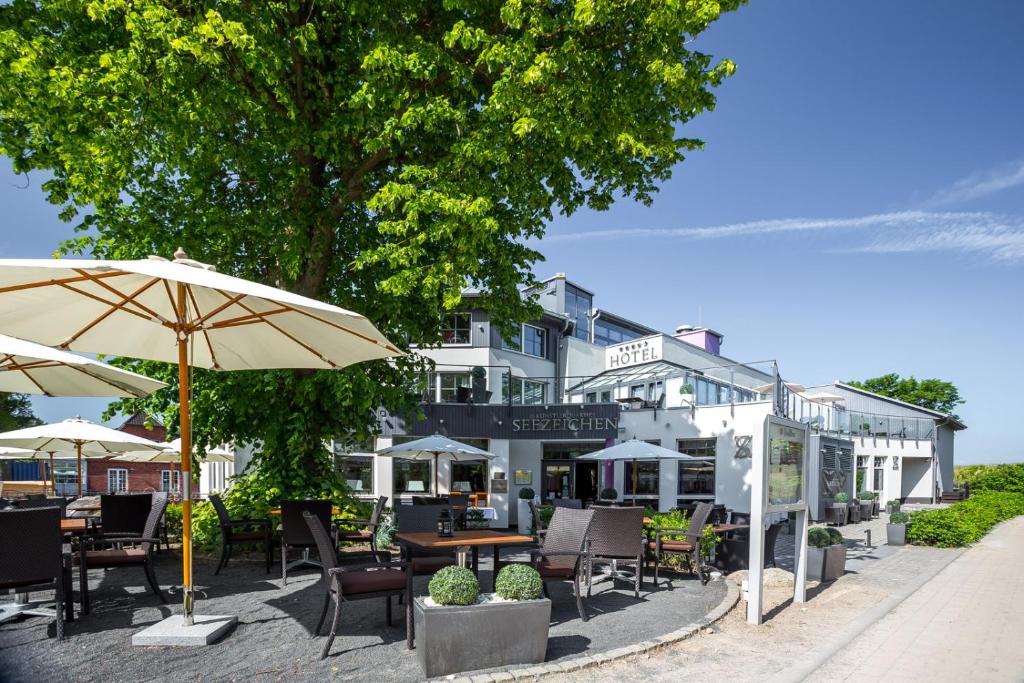 阿伦斯霍普Hotel Seezeichen Ahrenshoop的一间带桌椅和遮阳伞的餐厅