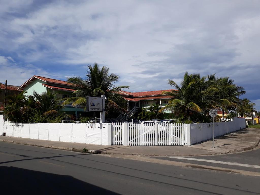 伊利亚孔普里达Pousada Canto da Ilha的棕榈树建筑前的白色围栏