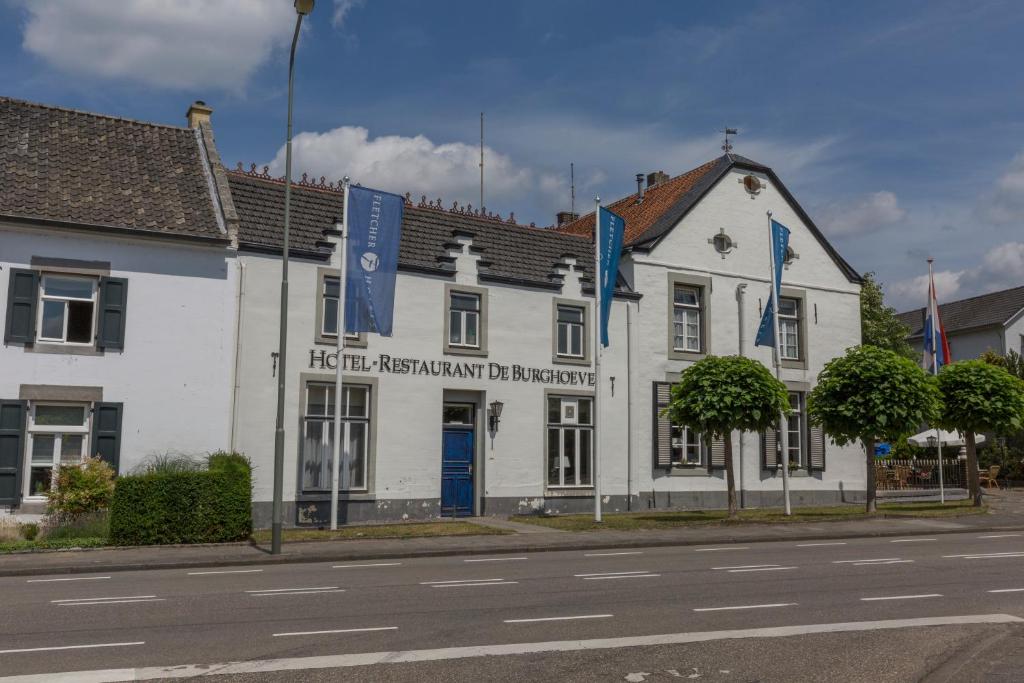 法尔肯堡德博格霍夫弗莱彻酒店及餐厅的街道上带有蓝旗的白色建筑