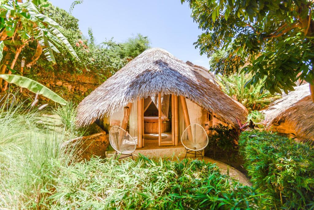 乌鲁瓦图巴厘竹子别墅的一座带两把椅子和茅草屋顶的小房子
