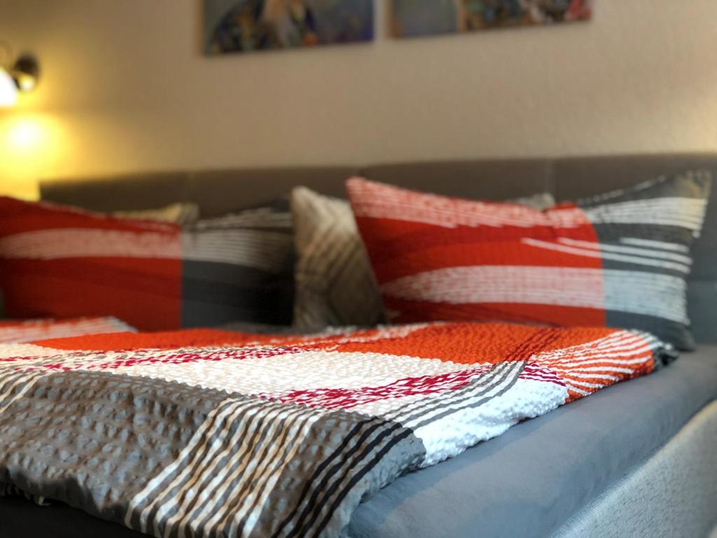 HörschelPension "Tor zum Rennsteig"的一张带红白毯子和枕头的床