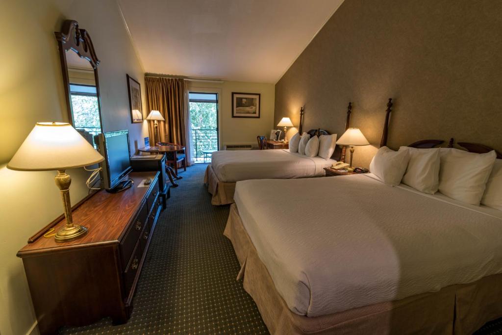 LakevilleInterlaken Inn的酒店客房设有两张床和一张带台灯的书桌。