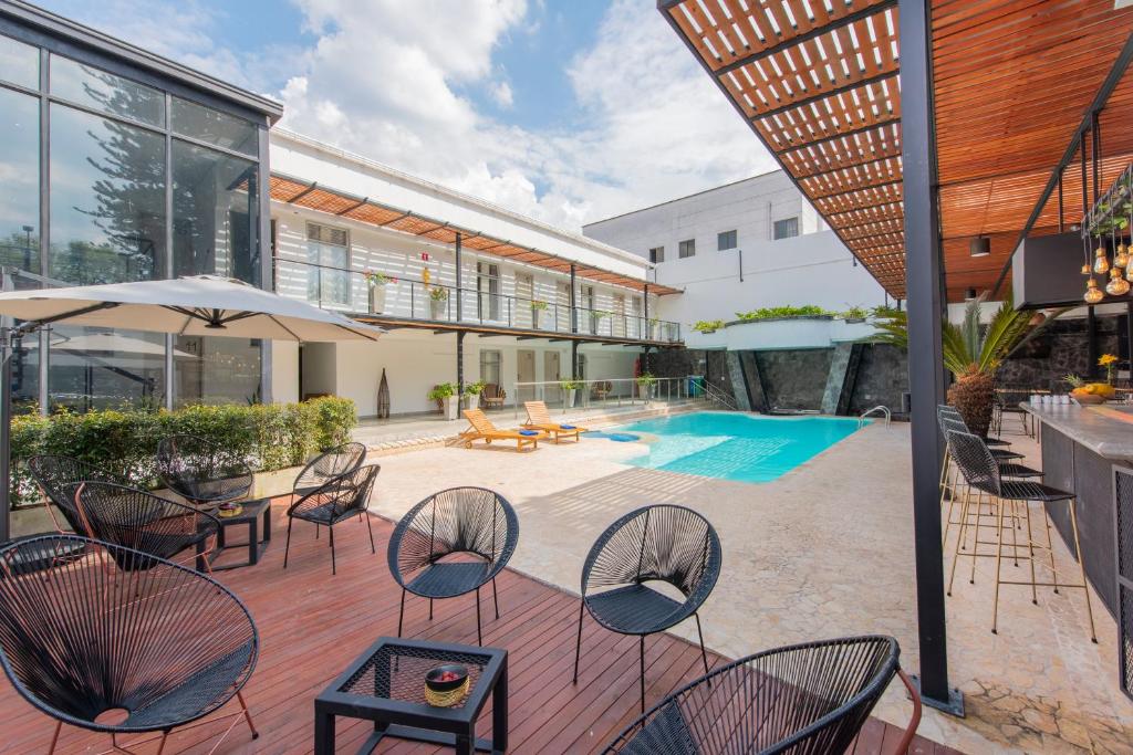 麦德林Medellín Vibes Hostel的一个带桌椅的庭院和一个游泳池