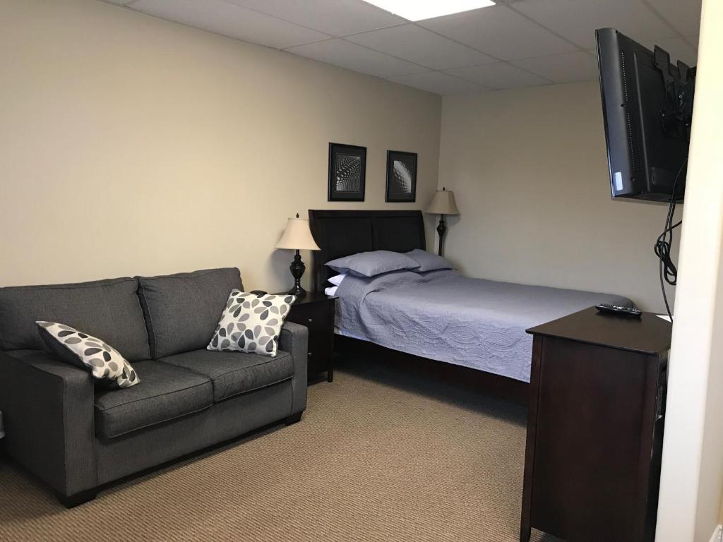 克拉伦维尔Riverview Suites的一间卧室配有一张床、一张沙发和一台电视