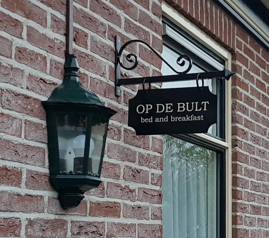 RasquertOp de Bult的街道标志附在砖砌建筑上,有街灯