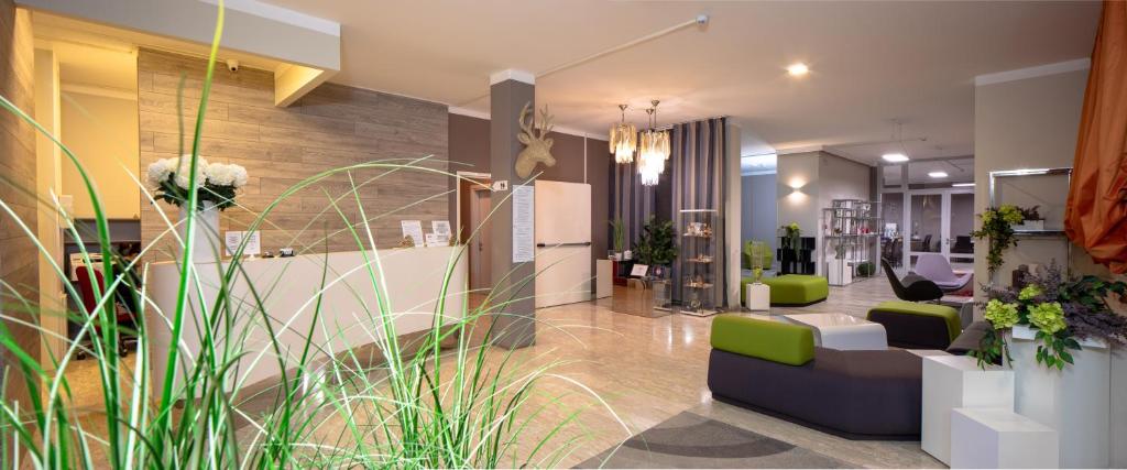 阿尔塔泰尔梅Hotel Alla Fonte的大堂拥有绿色的白色家具和植物