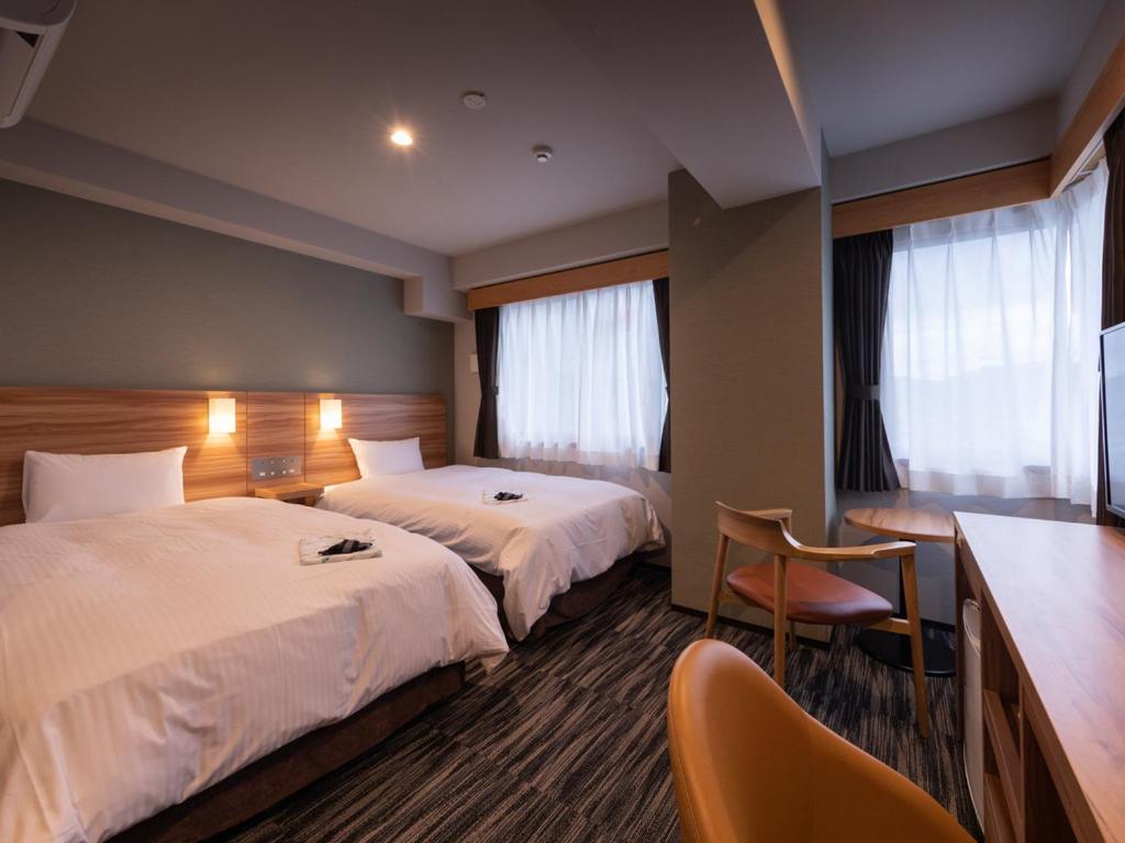 武雄市武雄艾克麦中心酒店的酒店客房配有两张床和一张书桌