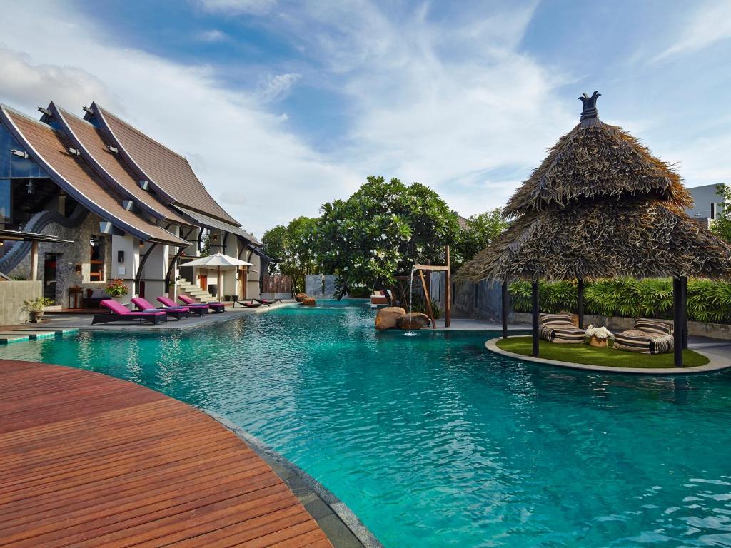 农布芭堤雅别墅酒店的度假村的游泳池,带椅子和茅草屋顶