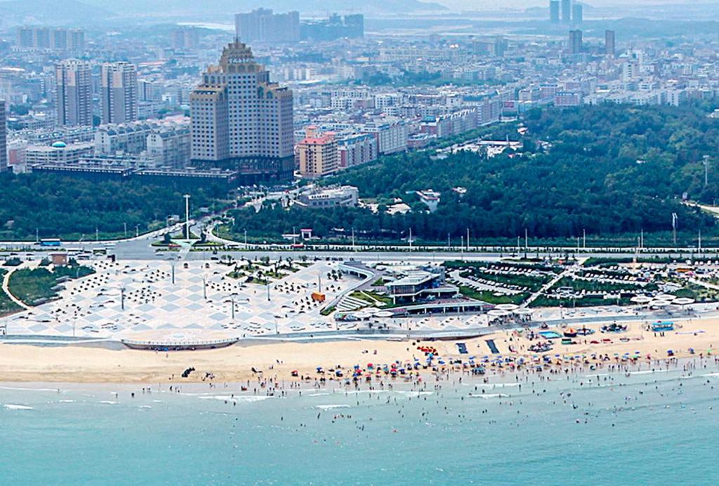 平潭平潭宇诚海景蓝眼智能酒店的一片海滩,上面有人,后面有城市