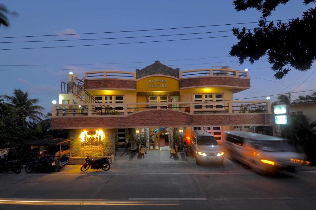 巴斯科Batanes Seaside Lodge & Restaurant的街上的一座建筑,汽车驶过