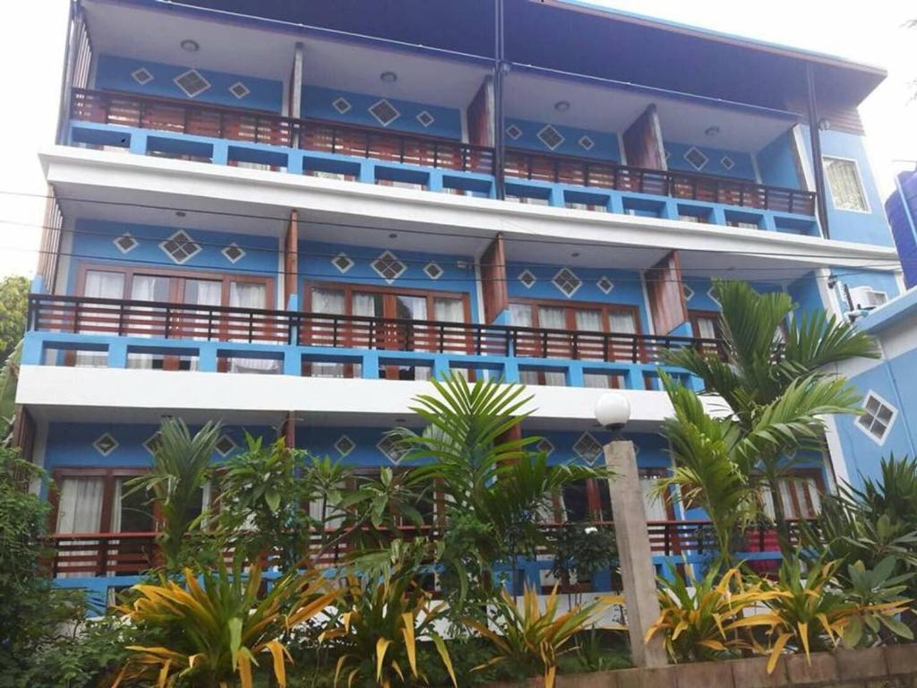 涛岛Mint Guesthouse的一座蓝色的建筑,前面有棕榈树