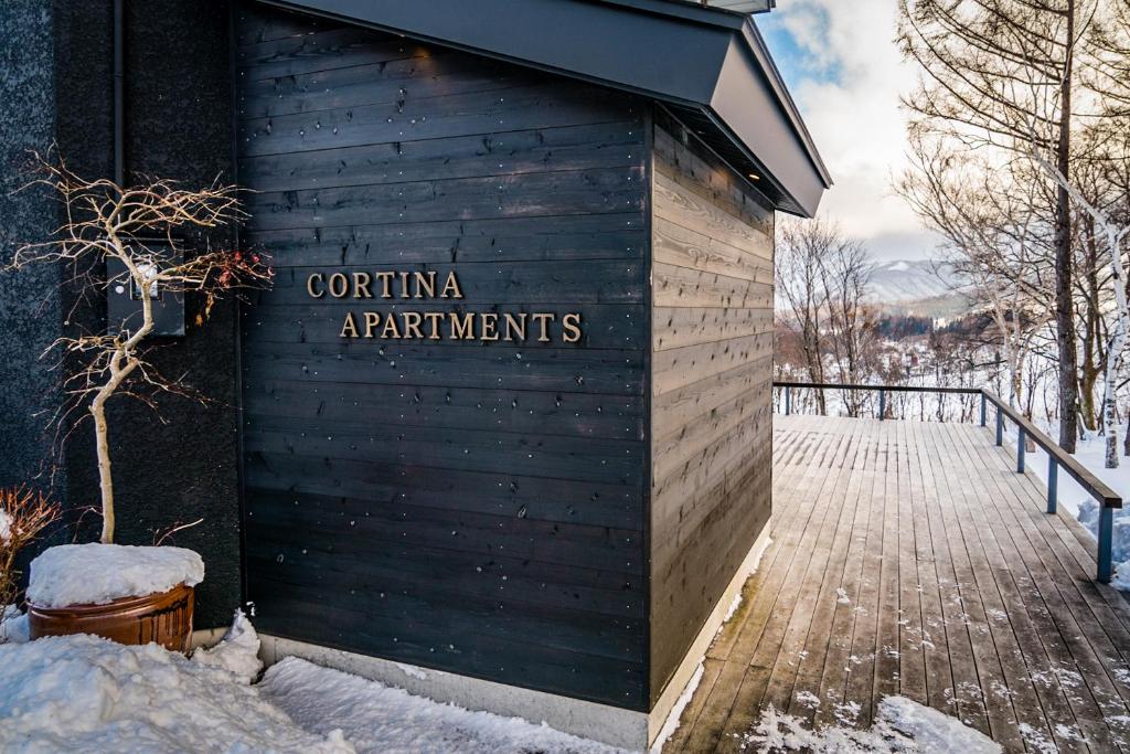 小谷村Cortina Apartment的雪中建筑物的侧面标志