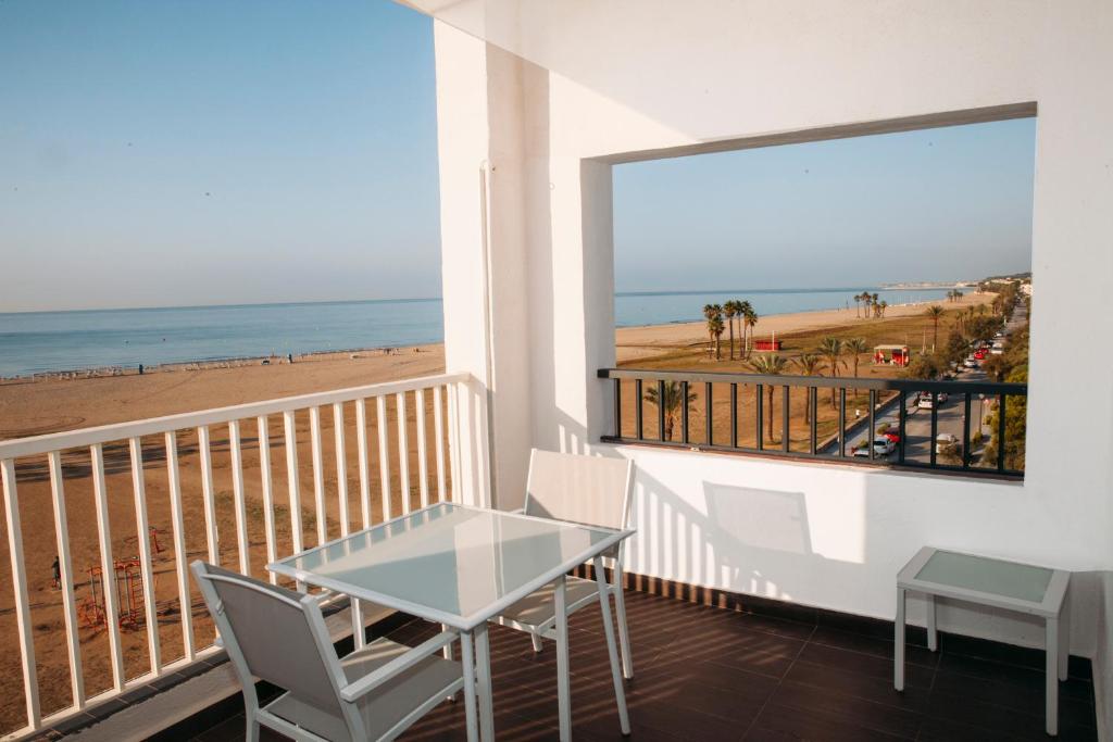 科马鲁加布里斯玛套房酒店的阳台配有桌子,享有海滩美景