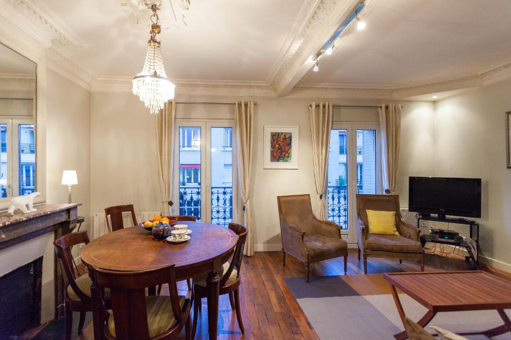 巴黎Greeter-Appartement Haussmannien avec balcon的客厅配有桌椅和电视。