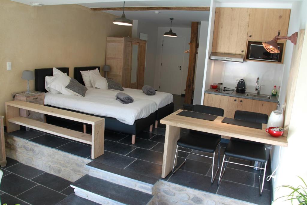 赫林贝亨Logies Tommenmolen的一间卧室配有一张床铺和一张桌子,还设有一间厨房