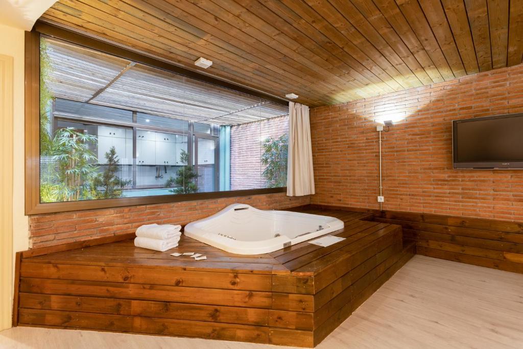 巴塞罗那DV公寓 的一间带浴缸的浴室和砖墙上的电视