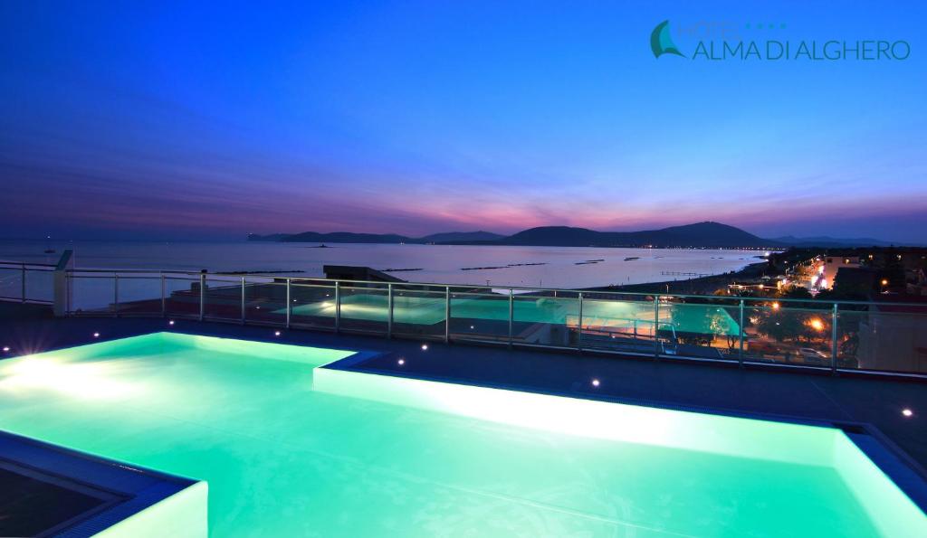 阿尔盖罗阿尔玛迪阿尔盖罗酒店的一座游泳池,在晚上在一座建筑的顶部