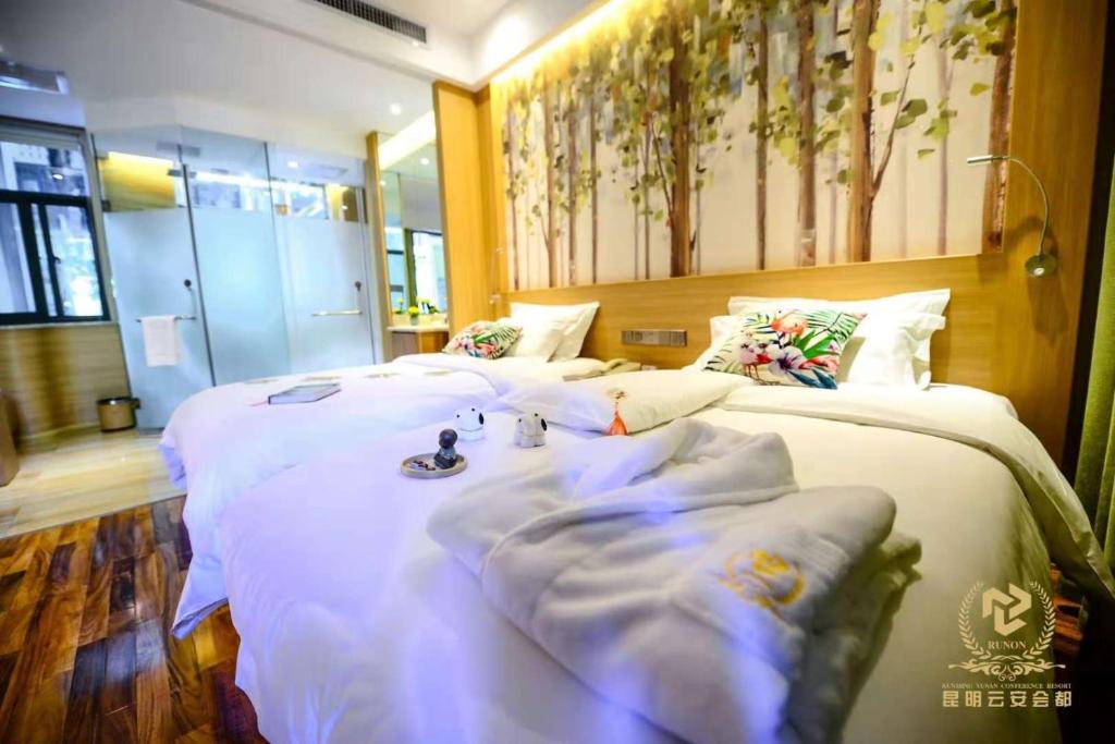 昆明昆明云安会都酒店的配有白色床单的酒店客房内的两张床