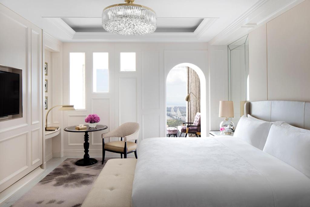 海口海口朗廷酒店的白色卧室配有一张大床和一张桌子