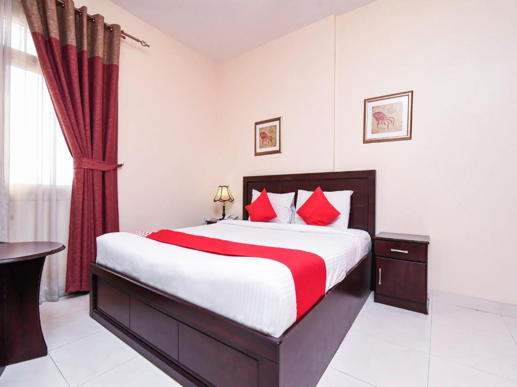 阿吉曼Paradise Inn 1 Tabasum Group的一间卧室配有一张带红色枕头的大床