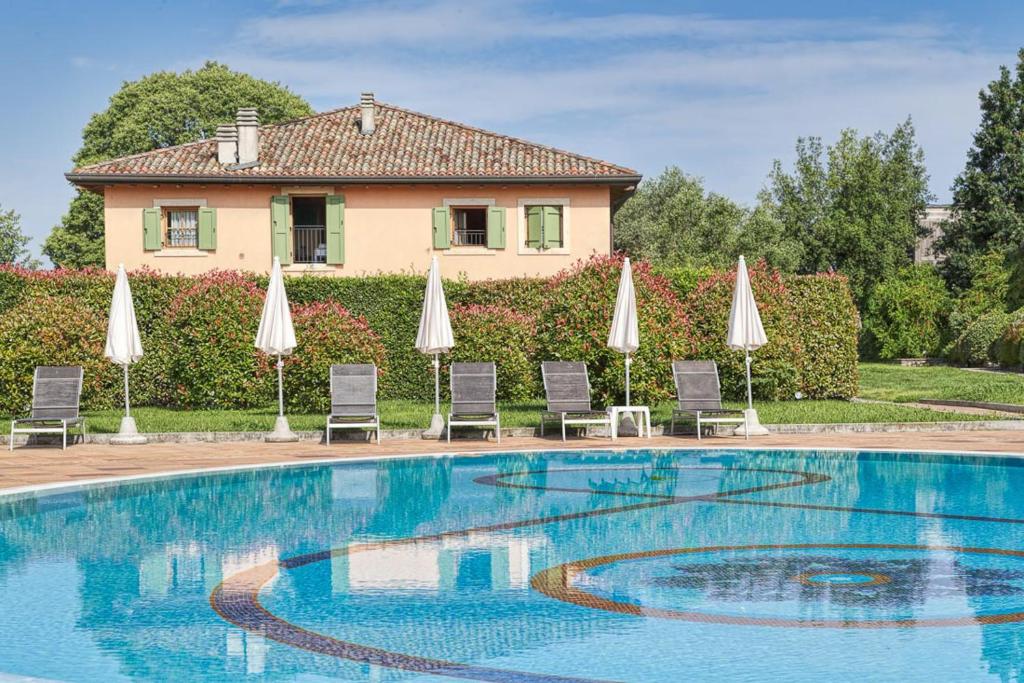 佩斯基耶拉德加达活力帕拉迪索高尔夫酒店的一个带遮阳伞和椅子的游泳池以及一座房子